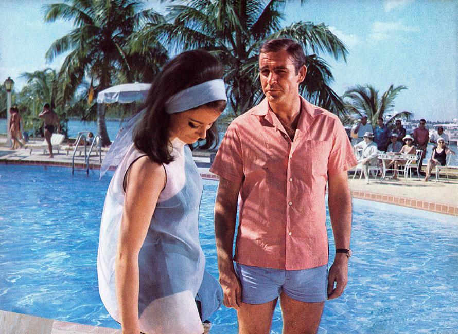 Sean Connery in costume azzurro e camicia rosa a bordo piscina con una donna