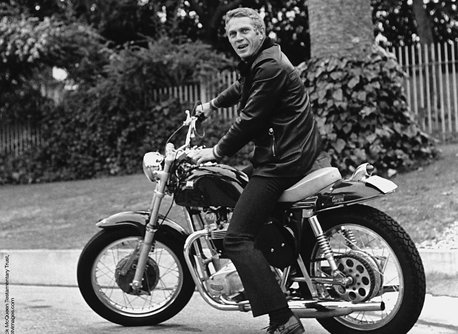 Fotografia in bianco e nero di Steve McQueen in moto con una giacca cerata