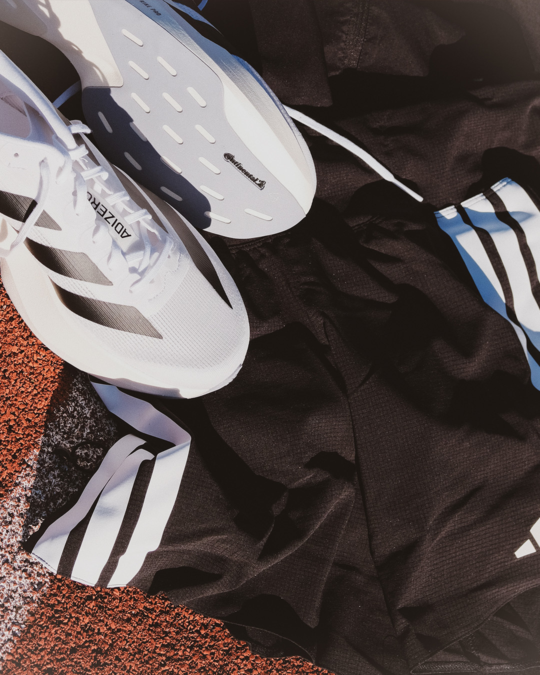 Scarpe da running bianche e abbigliamento sportivo nero su una pista di atletica