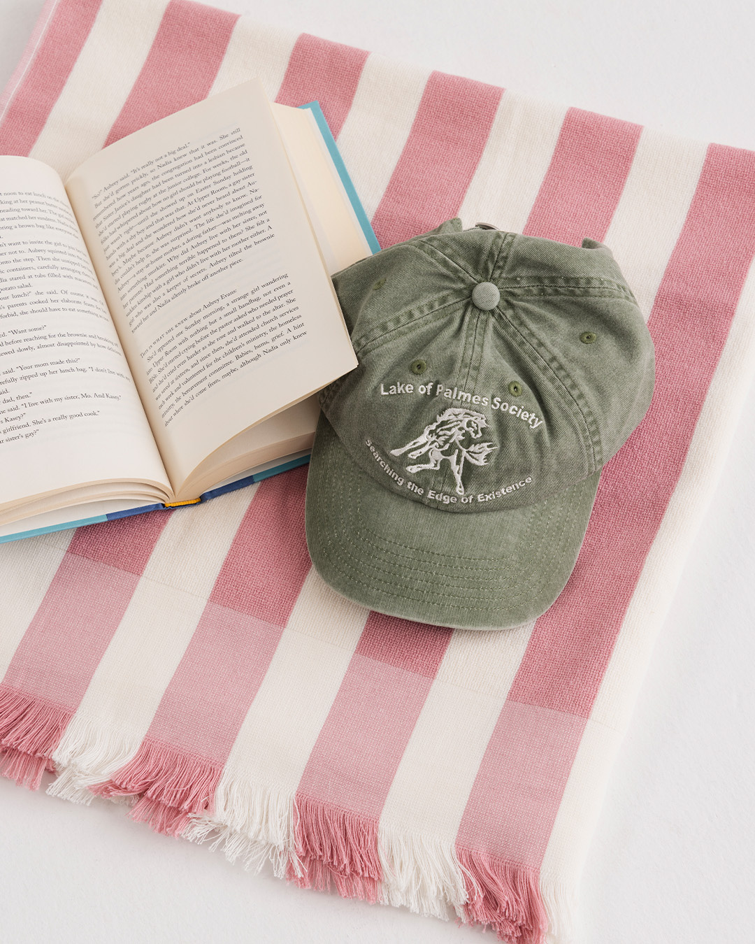 Libro aperto e cappellino verde su un telo mare a righe