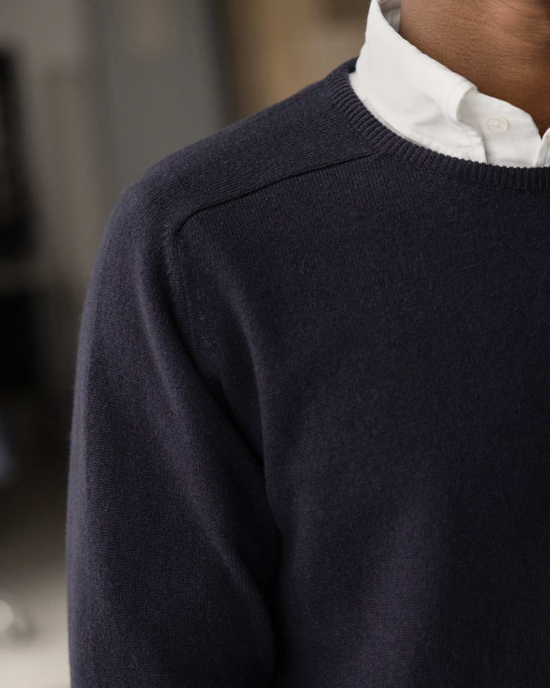 Primo piano di un uomo in pullover blu scuro sopra una camicia bianca