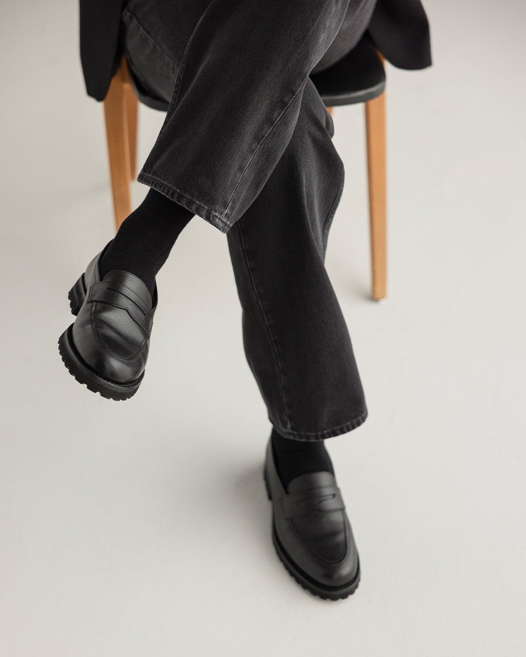 Primo piano di mocassini neri e pantaloni neri di un uomo seduto