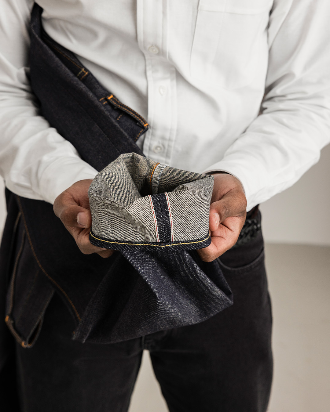 Mani che mostrano l'orlo risvoltato con cimosa selvedge di un paio di jeans scuri