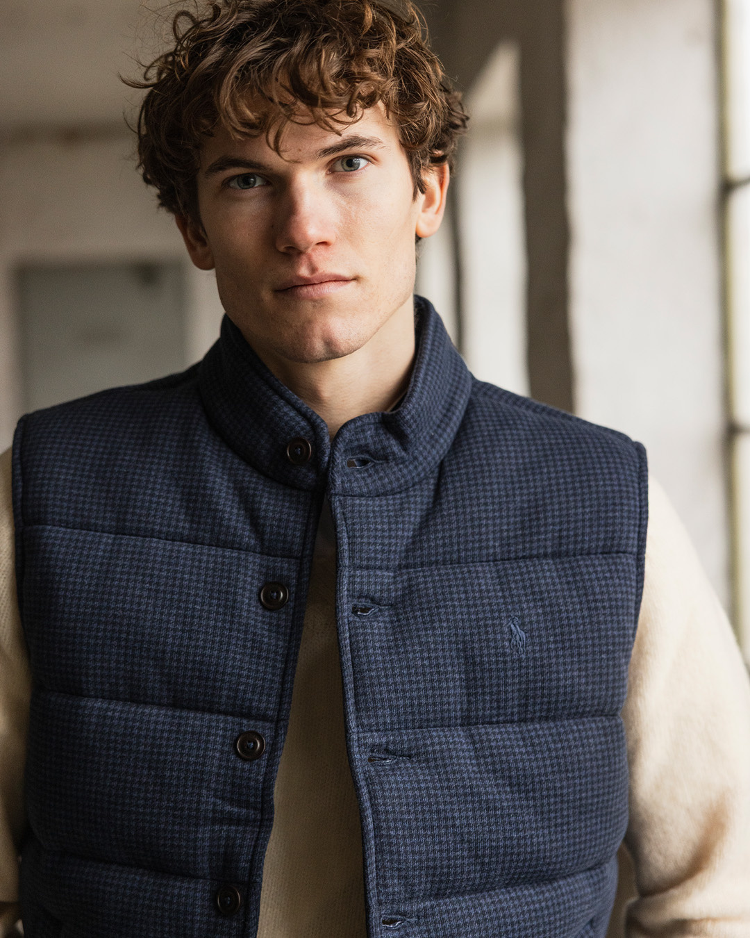 Uomo in gilet imbottito blu con motivo pied-de-poule di Polo Ralph Lauren sopra un maglione chiaro