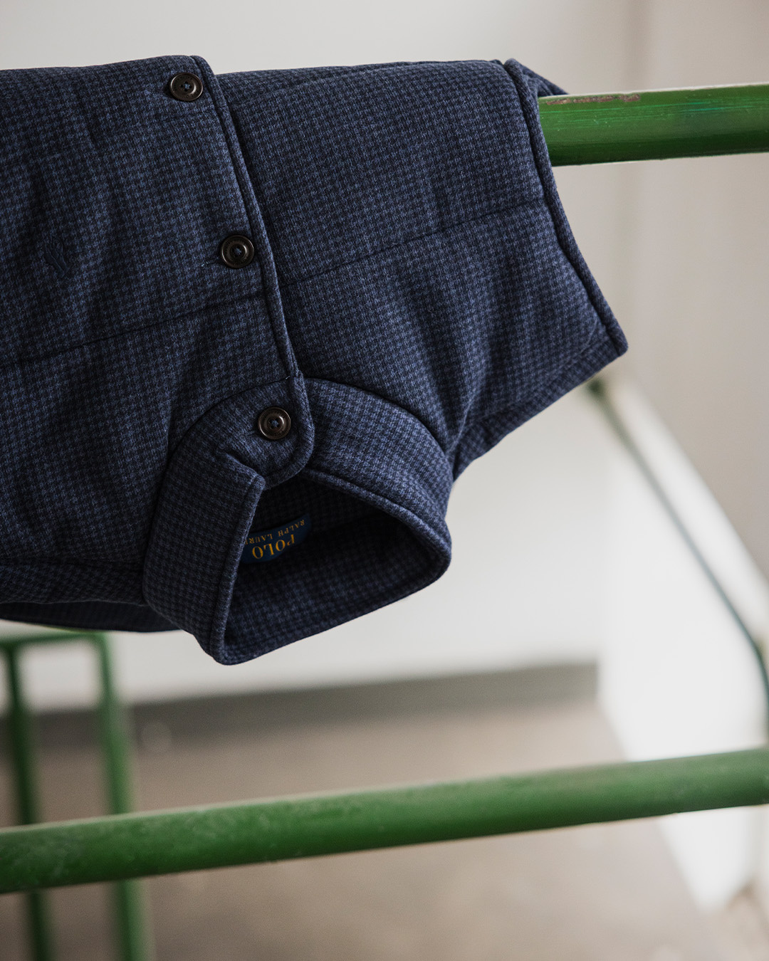 Gilet blu navy appeso a una ringhiera verde