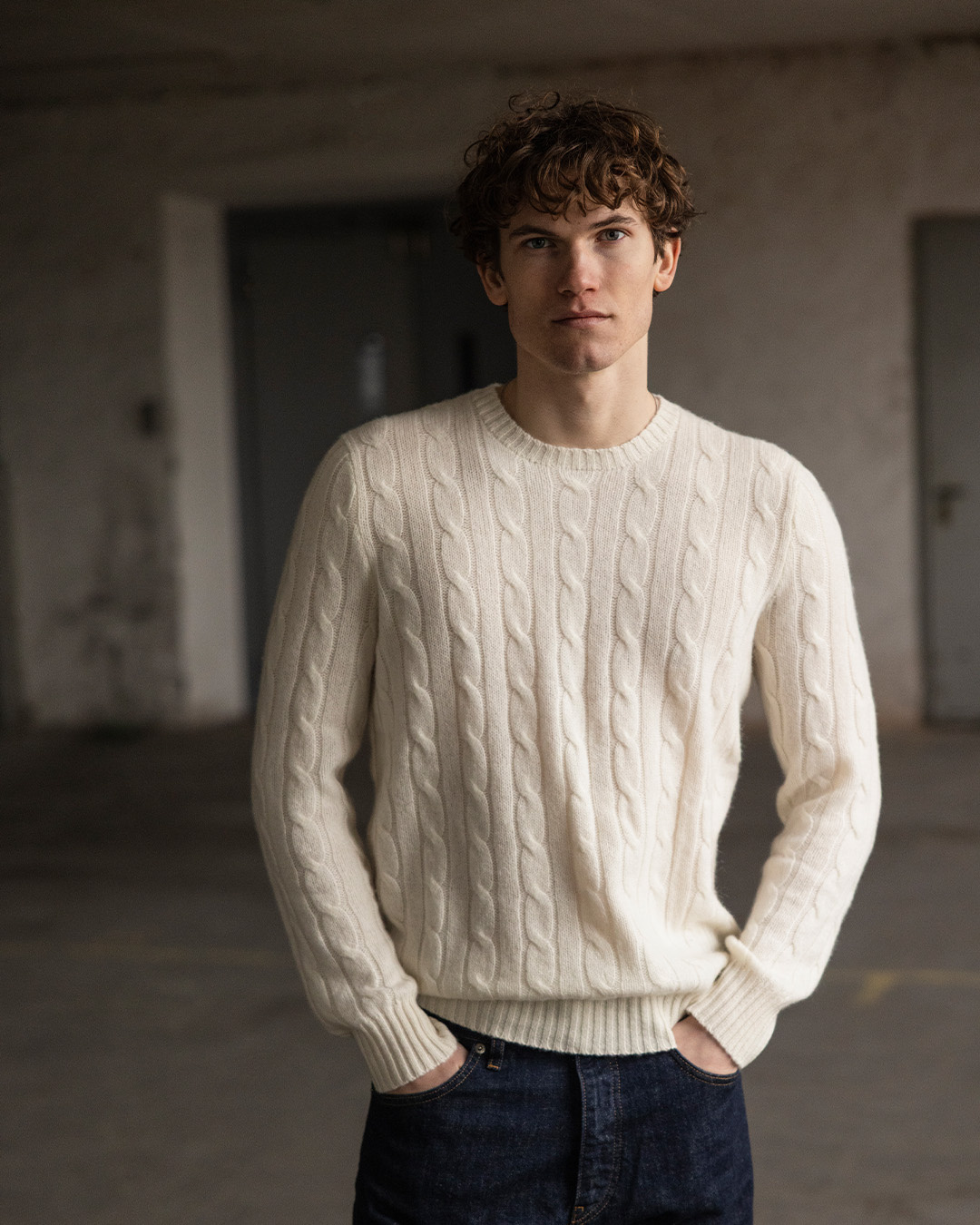 Uomo in maglione a trecce color crema e jeans