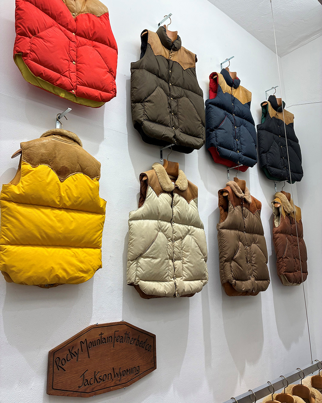 Gilet piumini colorati di Rocky Mountain Featherbed su una parete bianca