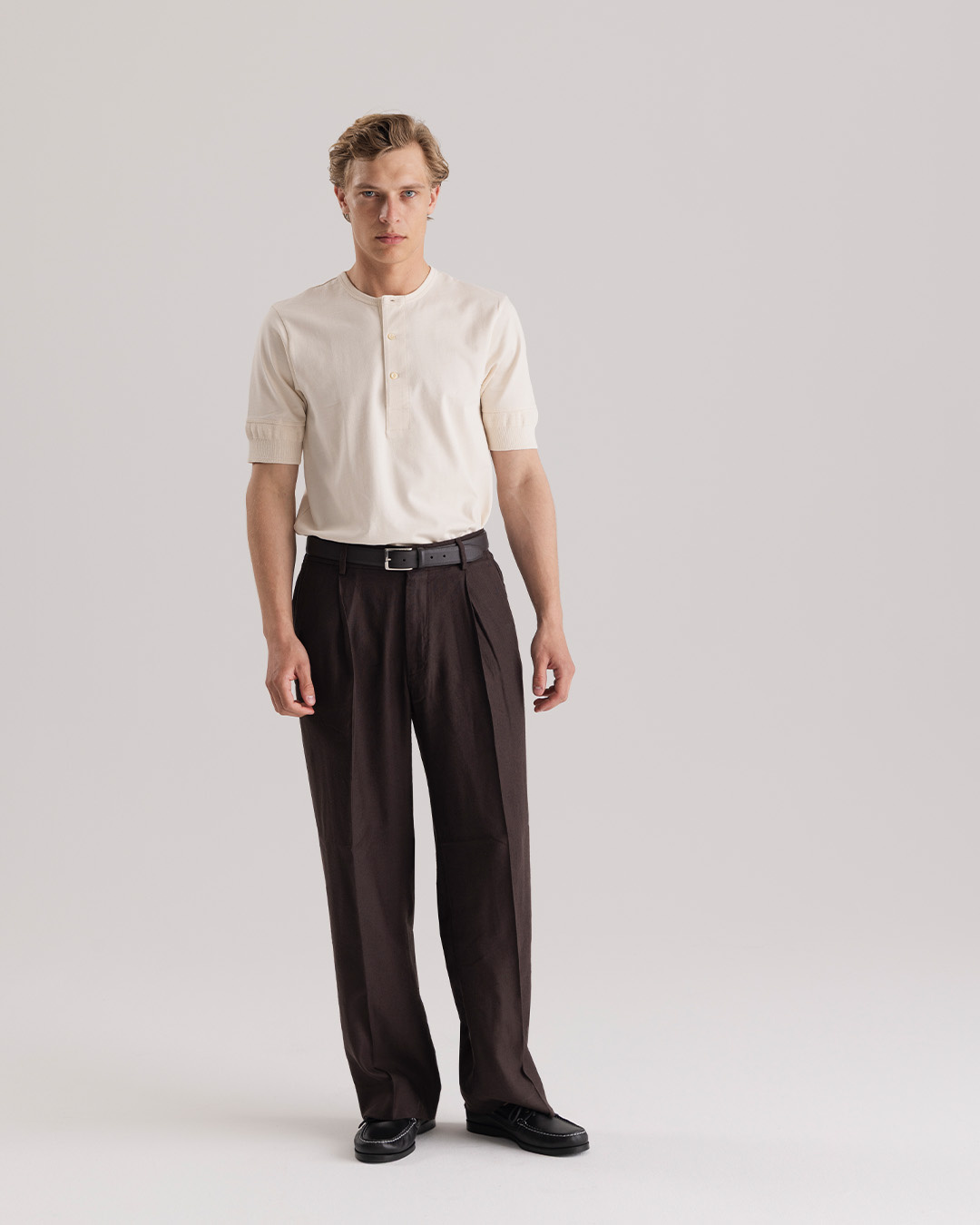Uomo in henley bianca e pantaloni da abito marroni a vita alta