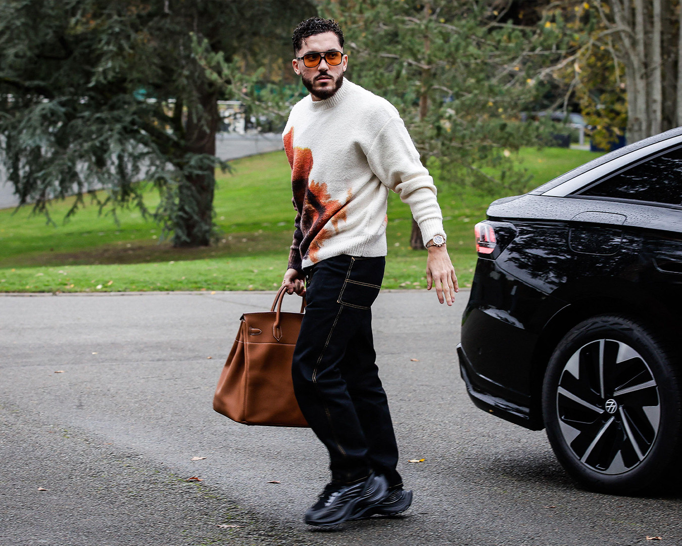 Rayan Cherki in maglione fantasia con una borsa Hermès marrone