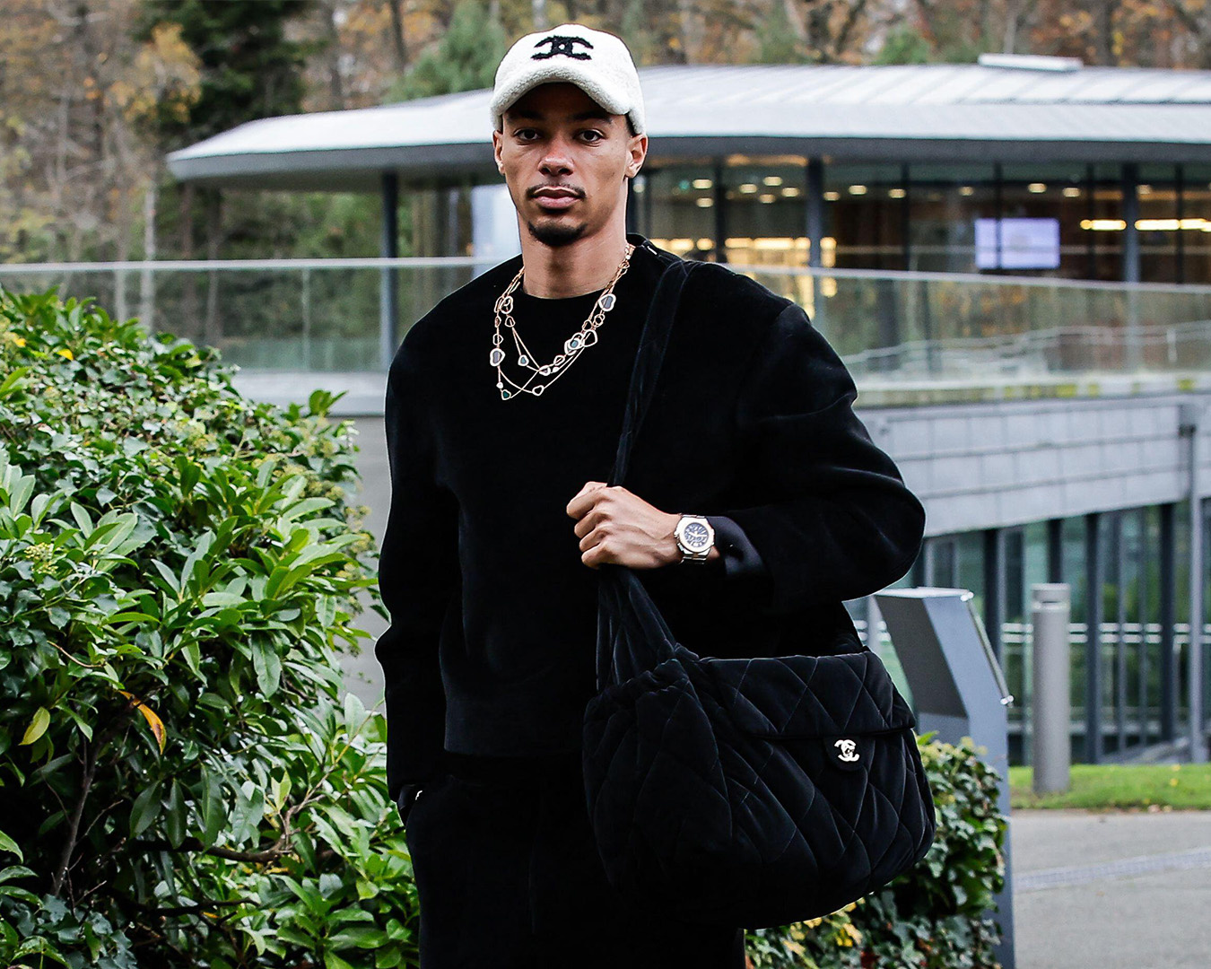 Hugo Ekitike in total black e cappellino bianco con una borsa trapuntata Chanel