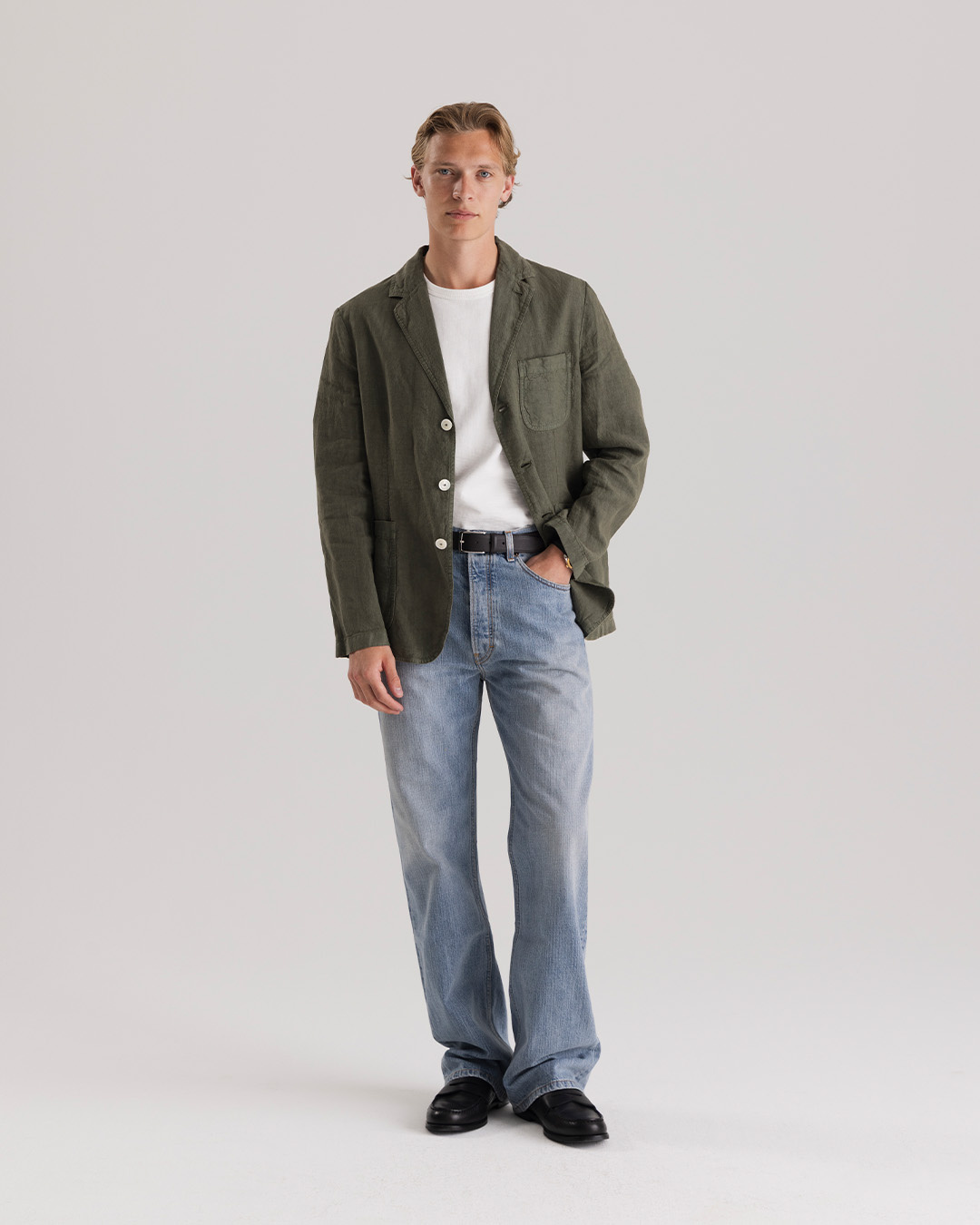 Uomo in giacca di lino verde, t-shirt bianca e jeans chiari