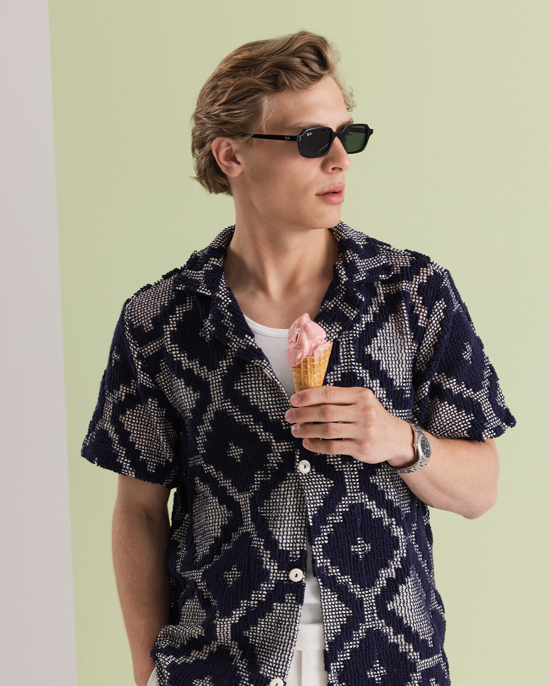 Uomo con occhiali da sole e camicia resort fantasia che tiene un gelato