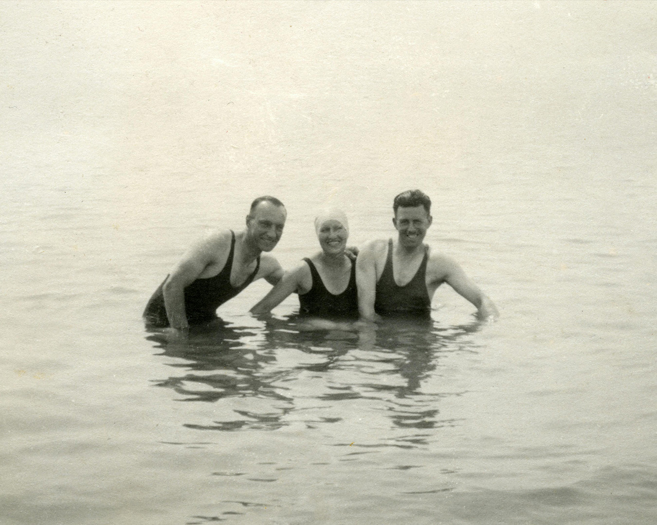 Vecchia fotografia di tre persone in costumi da bagno senza maniche in acqua