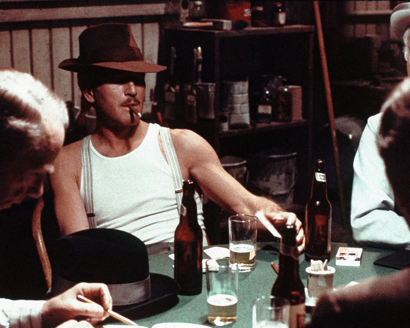Paul Newman in canottiera bianca e cappello a un tavolo da gioco in La stangata